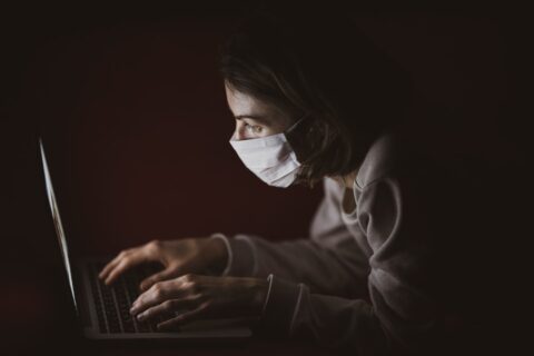 picture of a woman in a mask typing on a computer